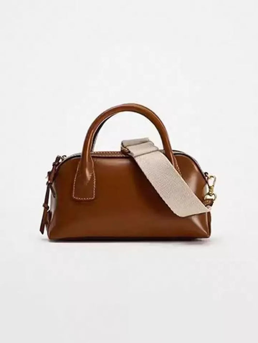 Brown handbag with a beige strap on a light gray background